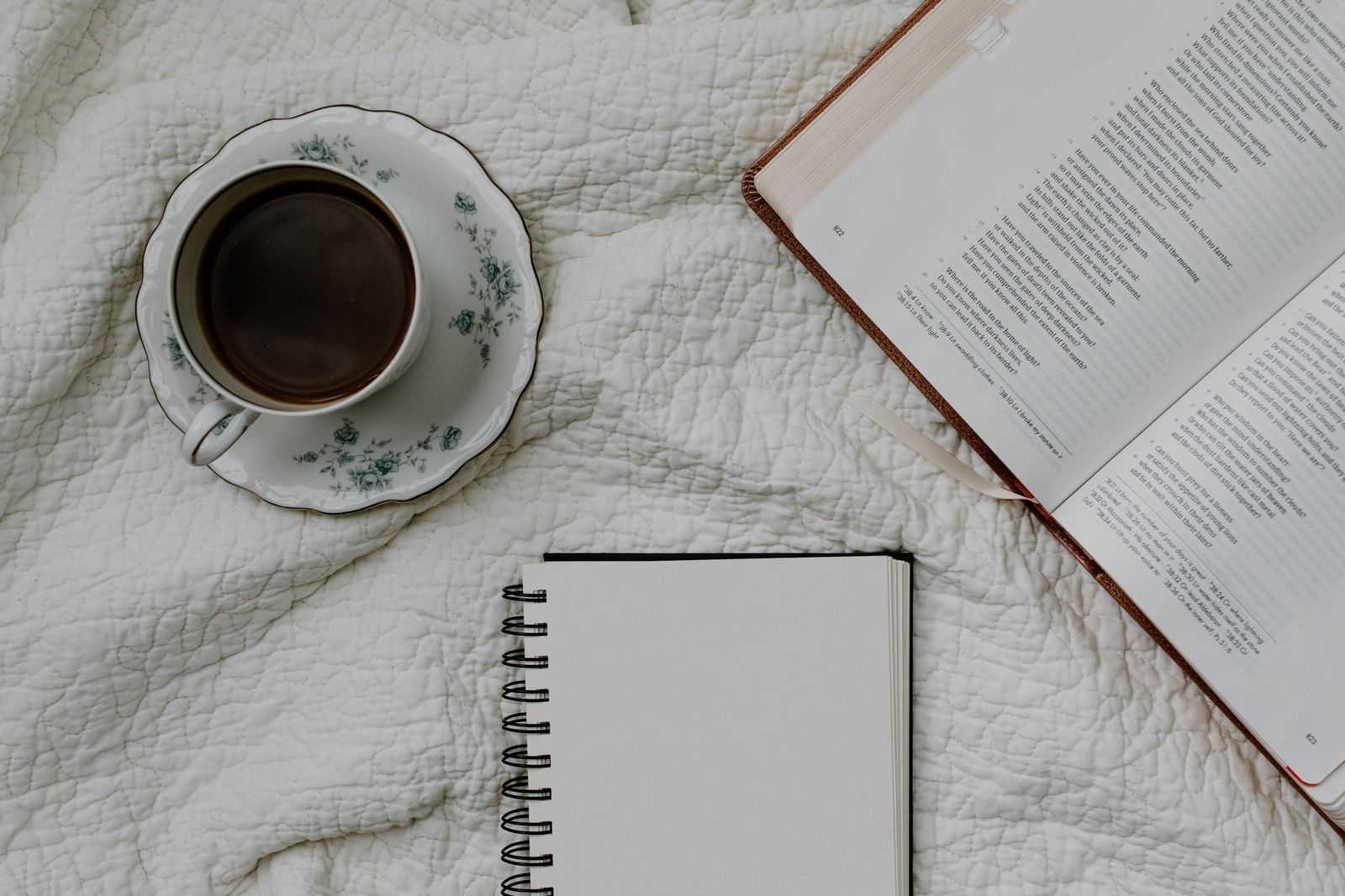 An open Bible beside a cup of coffee in soft morning light